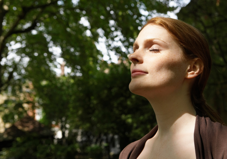 Woman standing in nature with eyes closed, embracing stillness and inner peace